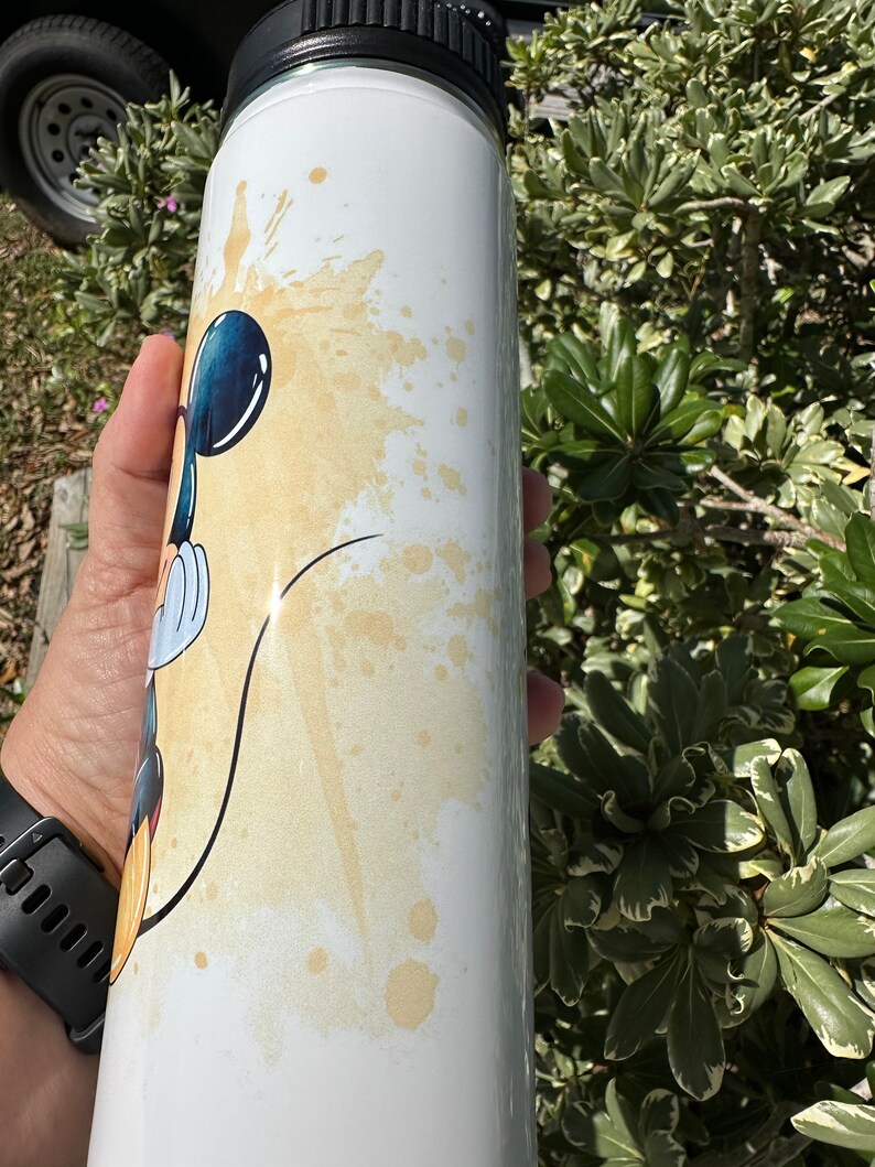 May include: White stainless steel water bottle with a black lid and a cartoon image of Mickey Mouse in a yellow and white watercolor design.