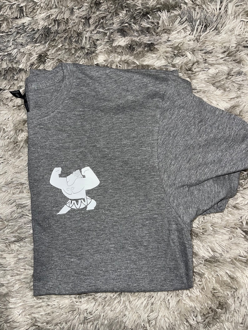 May include: A heather grey t-shirt featuring a white graphic of a cartoon character flexing its muscles.