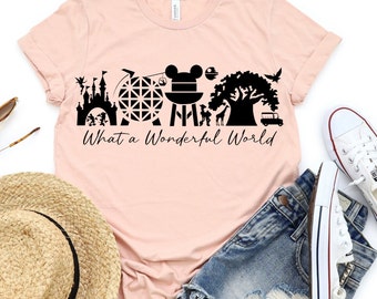 May include: A pink t-shirt with a black graphic of various Disney park icons, including Cinderella's Castle, Spaceship Earth, Mickey Mouse, and the Tree of Life. The text "What a Wonderful World" is printed below the graphic.