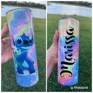 Puede incluir: Un vaso de acero inoxidable azul y blanco con un patr&oacute;n de te&ntilde;ido anudado y una imagen de dibujos animados de Stitch de Lilo & Stitch sosteniendo una mu&ntilde;eca. El vaso tiene el nombre "Marissa" escrito en &eacute;l.