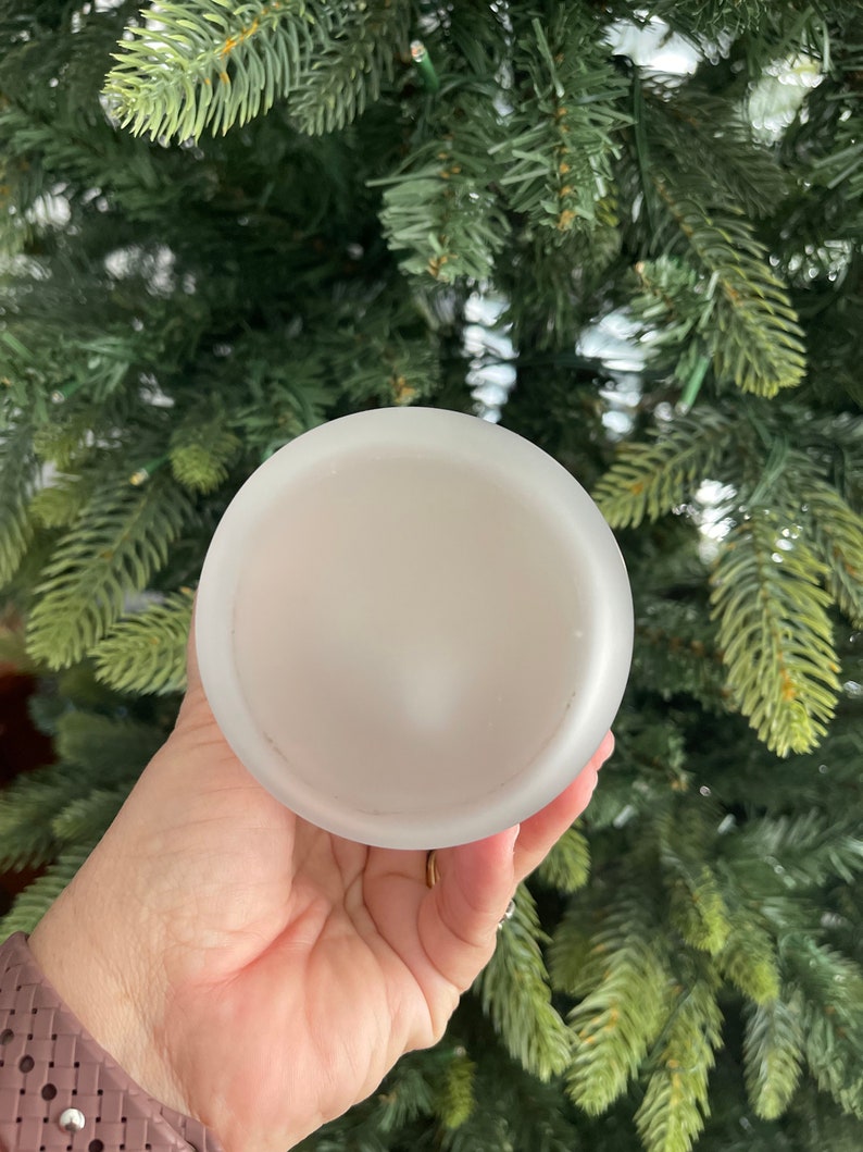 May include: A white frosted glass candle holder with a smooth, rounded surface.
