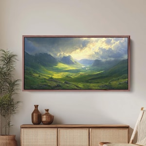 May include: A framed landscape painting depicting a valley with rolling green hills and a river winding through the center. The sky is a mix of blue and gray with white clouds and a bright sun shining through.