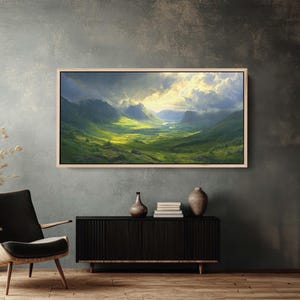 May include: A framed landscape painting depicting a valley with rolling green hills and a river winding through it. The sky is cloudy with a bright light shining through the clouds.