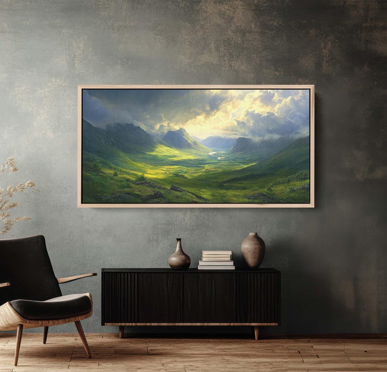 May include: A framed landscape painting depicting a valley with rolling green hills and a river winding through it. The sky is cloudy with a bright light shining through the clouds.