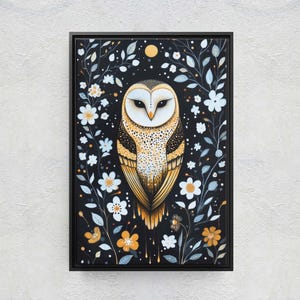 May include: A black framed canvas painting of a barn owl with yellow and brown feathers, perched in a field of white flowers with blue and green leaves on a black background.