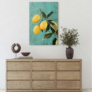 May include: A painting of a lemon tree branch with yellow lemons against a teal background. The painting is framed and hanging on a white wall above a wooden dresser.