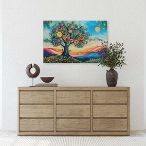 May include: A colorful painting of a tree with flowers and a sunset in the background. The painting is framed and hanging on a white wall above a wooden dresser.