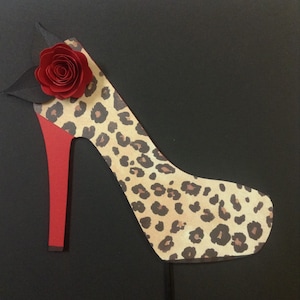 May include: A leopard print high heel shoe with a red heel and a red rose on the front.