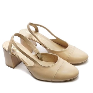 May include: A pair of beige leather heeled slingback shoes with a closed toe and a block heel.