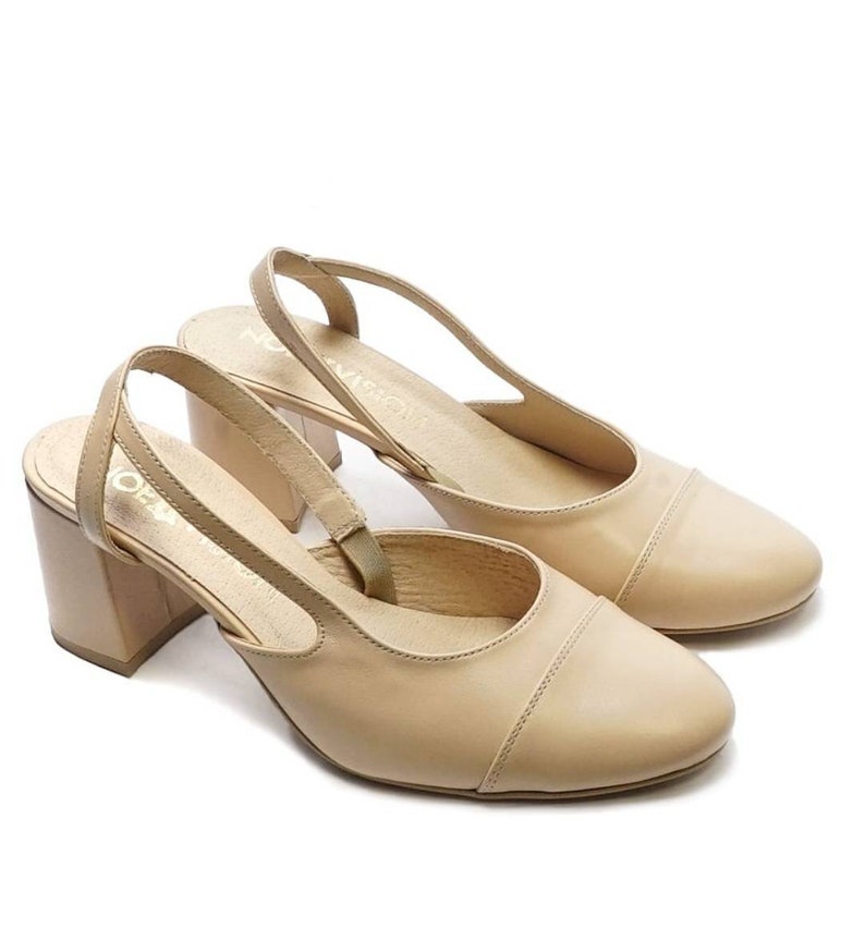 May include: A pair of beige leather heeled slingback shoes with a closed toe and a block heel.