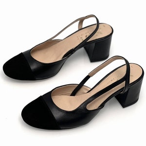 May include: Black leather slingback heels with a suede toe cap and a block heel.