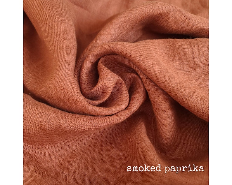 K&ouml;nnte beinhalten: Nahaufnahme eines weichen, strukturierten Stoffes in einem satten, erdigen Braunton. Der Stoff ist zerknittert und gefaltet, was einen nat&uuml;rlichen, organischen Look erzeugt. Der Text "smoked paprika" ist am unteren Rand des Bildes sichtbar.