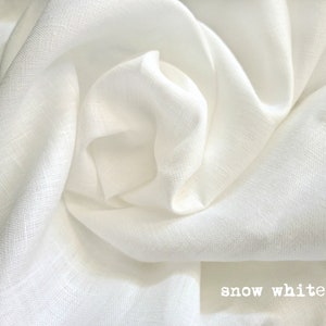 K&ouml;nnte beinhalten: Nahaufnahme eines wei&szlig;en Leinenstoffs, der seine Textur und seinen weichen Fall zeigt. Der Stoff ist glatt und knitterfrei, mit einem dezenten Glanz. Der Text "snow white" ist unten im Bild sichtbar.