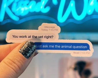 May include: Two stickers in the shape of text message bubbles. One reads "You work at the vet right?" and the other says "Just ask me the animal question." A neon sign in the background says "Kissed Whis".