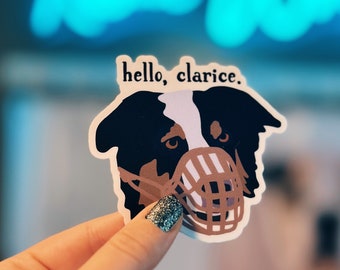 Può includere: Un adesivo di un cane bianco e nero con un muso marrone. L'adesivo ha il testo "hello, clarice." stampato su di esso.