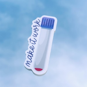 May include: A sticker featuring a clear test tube with a blue cap and a small amount of red liquid at the bottom. The words "make it work" are written in blue script along the side of the tube.