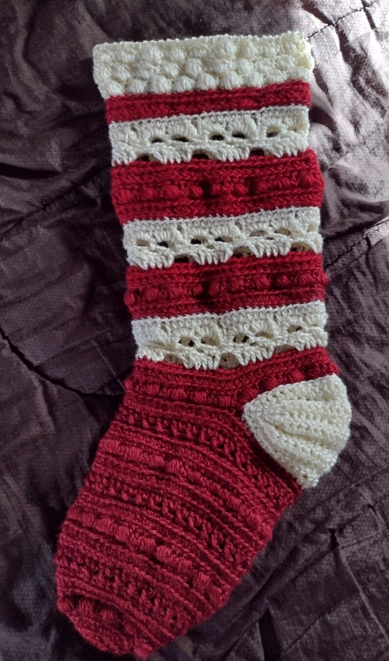 May include: A red and white crocheted Christmas stocking with a white crocheted cuff and a white crocheted toe.