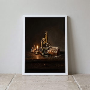 May include: A framed wall art print depicting a brass microscope on a dark wooden table, illuminated by a small oil lamp. Beside the microscope are two glass vials and a wooden rack containing several glass microscope slides in a dark room.