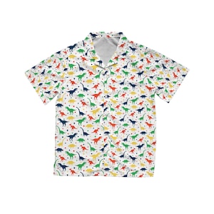 May include: White button-down shirt with a colorful dinosaur pattern. The short-sleeved shirt features a repeating design of various dinosaurs in red, green, yellow, and blue, with small heart shapes scattered across the fabric.