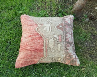 May include: A red and beige throw pillow with a traditional Turkish kilim pattern. The pillow is made of woven fabric and has a fringed edge.