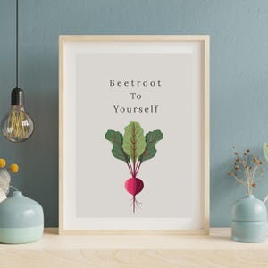 May include: A framed print with the text "Beetroot To Yourself" above a stylized illustration of a beetroot. The beetroot has a red bulb, green leaves, and thin roots. The frame is light brown.