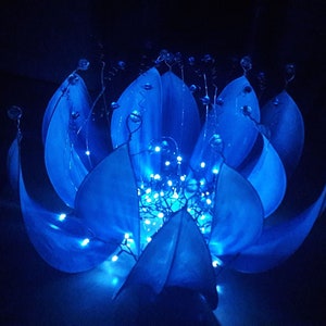 Pode incluir: Uma escultura de flor de papel azul com luzes brancas enfiadas pelos p&eacute;talos.