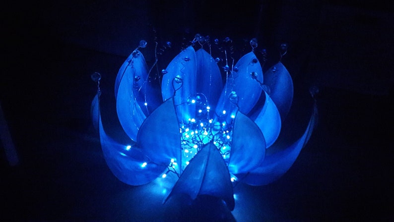 Pode incluir: Uma escultura de flor de papel azul com luzes brancas enfiadas pelos p&eacute;talos.