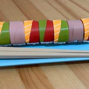 May include: A blue plate with a set of colourful sushi rolls and a pair of wooden chopsticks.