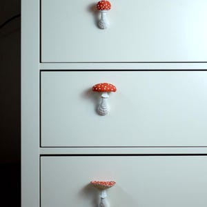 May include: White chest of drawers with three drawers featuring red and white mushroom-shaped drawer pulls.