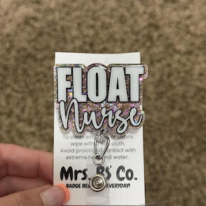 May include: A badge reel with the words "FLOAT Nurse" in white lettering on a glittery background. The badge reel is attached to a white card with care instructions and the text "Mrs. BS Co. BADGE REELS EVERYDAY!"