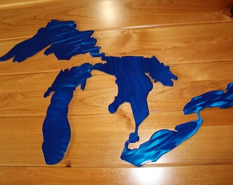 May include: A blue metal wall art sculpture depicting the Great Lakes of North America. The sculpture is made of metal and has a brushed finish.
