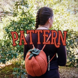 May include: A crocheted pumpkin backpack with green leaves. The backpack is orange and has a drawstring closure. The text "basicstitchcolorado" is visible on the backpack.