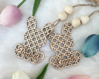Op de afbeelding: Twee houten bunny-vormige ornamenten met ingewikkelde uitgesneden ontwerpen. De ornamenten zijn gepersonaliseerd met de namen "Elizabeth" en "Kenneth".