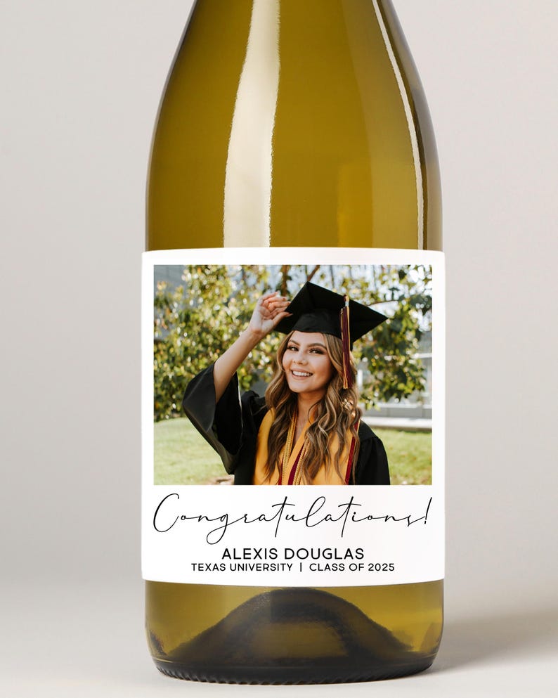 May include: A wine bottle with a personalised label celebrating graduation. The label displays a photograph of a graduate in cap and gown, with the text "Congratulations!", the graduate's name, university, and class year.