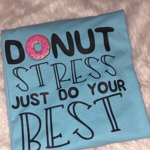 May include: Light blue t-shirt with a donut graphic and the text "Donut stress just do your best".