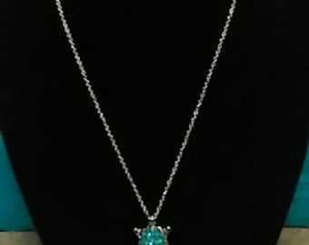 Op de afbeelding: Een zilveren ketting met een turquoise ster hanger.