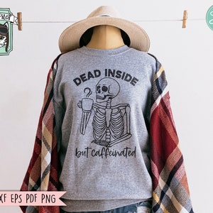 May include: A gray sweatshirt with a black graphic of a skeleton holding a coffee cup. The text "Dead Inside but Caffeinated" is printed below the skeleton.