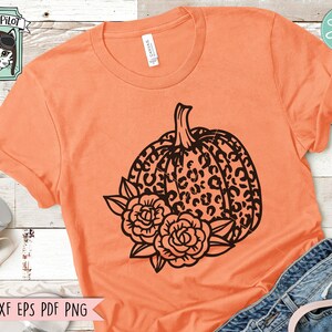May include: Orange t-shirt with a black and white leopard print pumpkin with black floral accents.