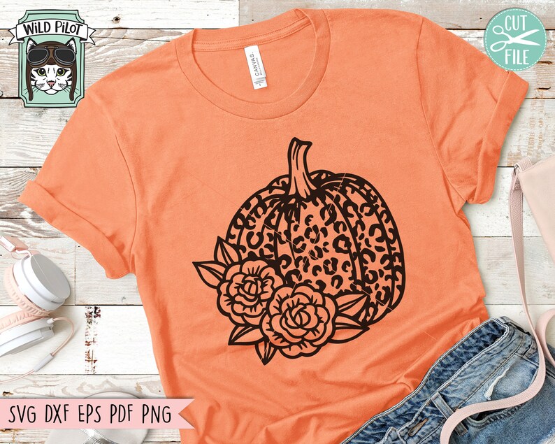May include: Orange t-shirt with a black and white leopard print pumpkin with black floral accents.