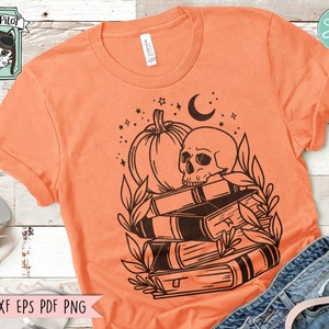 May include: Orange t-shirt with a black graphic of a skull, pumpkin, books, and crescent moon. The shirt also features the text "SVG DXF EPS PDF PNG" at the bottom. A Wild Pilot logo is in the upper left corner.