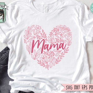 Pu&ograve; includere: Maglietta bianca con un design a forma di cuore rosa con la parola "Mama" circondata da elementi floreali.