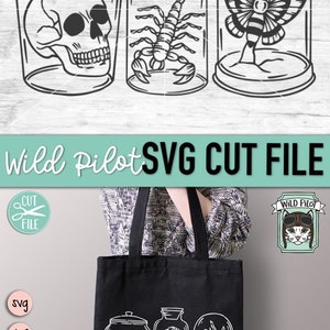 May include: A black tote bag with a white design of three glass jars containing a skull, scorpion, and butterfly. The text "Wild Pilot SVG Cut File" is at the top of the image.