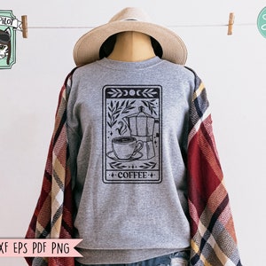 May include: A gray sweatshirt with a black and white graphic of a coffee pot, a cup of coffee, and the word "COFFEE" on it. The graphic is surrounded by a black border and has a moon and stars design at the top.