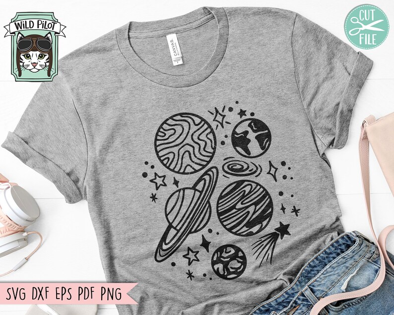 Pode incluir: Uma camiseta cinza com um design preto e branco de planetas, estrelas e um cometa. O design est&aacute; centralizado na camiseta.