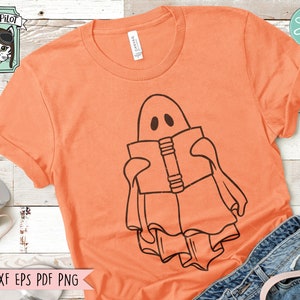 May include: A digital design featuring a ghost reading a book. The ghost is outlined in black and the book is filled in with black. The design is on a peach colored t-shirt.