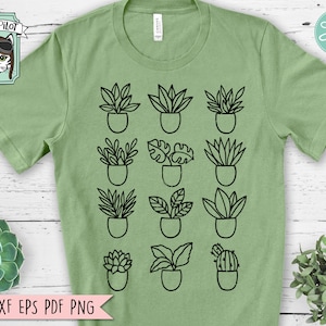 May include: A green t-shirt with a design of 15 potted plants in black outline. The plants are arranged in a grid pattern. The t-shirt has a crew neck and short sleeves. The text "WILD PILOT" is in a white box with a cartoon cat wearing aviator sunglasses in the top left corner of the image.
