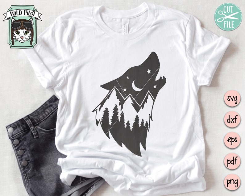 May include: A white t-shirt with a black silhouette of a wolf's head howling at the moon. The wolf's head is filled with a mountain range and pine trees. The moon is a crescent shape with stars around it.