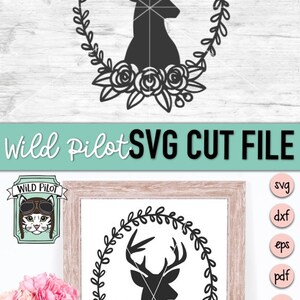 K&ouml;nnte beinhalten: Schwarz-wei&szlig;e Silhouette eines Hirschkopfes mit Geweih in einem Kranz aus Bl&auml;ttern und Blumen. Das Bild ist auf wei&szlig;em Hintergrund und tr&auml;gt die Aufschrift "Wild Pilot SVG Cut File".