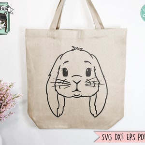 May include: A beige tote bag with a black outline of a bunny rabbit face. The bunny has large ears, big eyes, and a small nose.