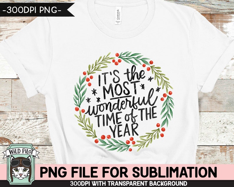 May include: White t-shirt featuring a watercolor wreath with green leaves and red berries. The text "IT'S the MOST wonderful TIME of THE YEAR" is in black script. A Wild Pilot logo is in the lower left corner.
